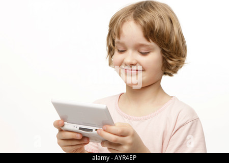 Otto-anno-vecchia ragazza che gioca con il suo computer da tasca Foto Stock