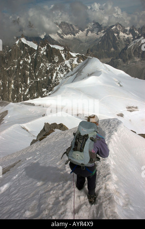 Una cordata lady scalatore scendendo una stretta dorsale nelle Alpi francesi, Chamonix, Francia. Foto Stock