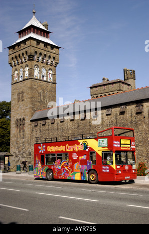Autobus turistico scoperto rosso parcheggiato accanto alla storica Torre dell'Orologio del Castello di Cardiff, Galles, Regno Unito. Tour panoramico iconico nella capitale gallese. Foto Stock