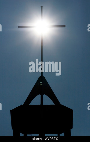 Sole che splende dietro una croce su di un campanile Foto Stock