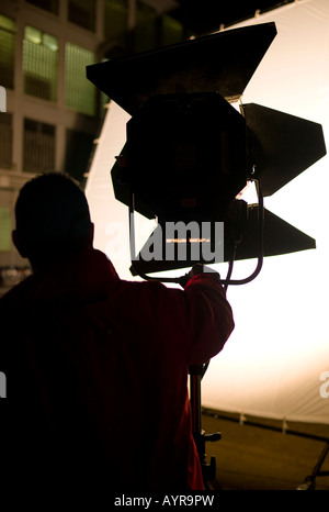 Tecnico luci impostazione di un proiettore su un set cinematografico in Germania, Europa Foto Stock