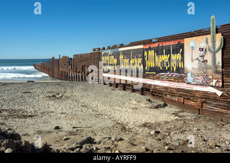 Stati Uniti messicani recinzione di confine in esecuzione nell'Oceano Pacifico con poster di avvertimento di morti accidentali di Tijuana, Messico Foto Stock