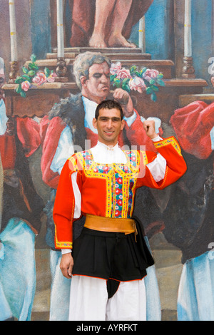 Uomo che indossa il costume tradizionale in piedi di fronte ad una parete murale nel villaggio di montagna di Fonni, Sardegna, Italia Foto Stock