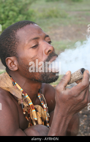 Africa Tanzania Lago Eyasi Hadzabe uomo fumo da un tradizionale tubo di argilla Foto Stock