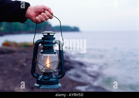 Man mano che trattiene il gas liquido lanterna di carburante sul roccioso riva del lago Superior Minnesota MN USA Foto Stock