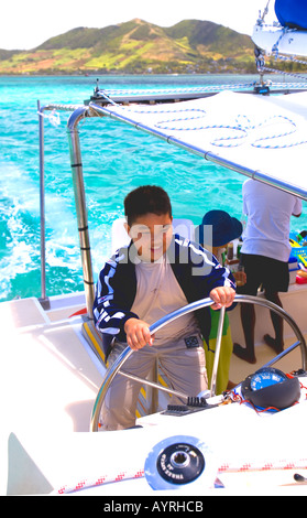 Il bambino tiene timone di catamarano Maurizio Foto Stock