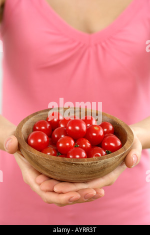 Donna che mantiene un recipiente con pomodori ciliegia Foto Stock