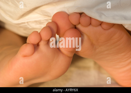 Bambino i piedi che spuntavano da sotto le lenzuola Foto Stock