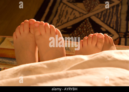 Donna adulto e bambino i piedi che spuntavano da sotto una coperta Foto Stock