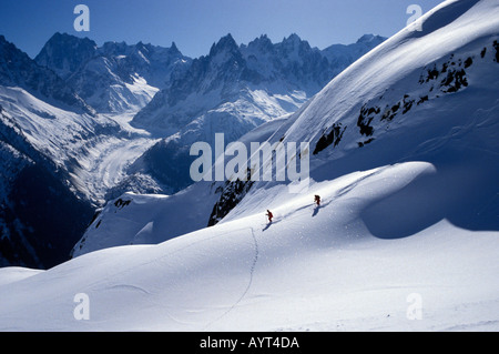 Due gli sciatori di discesa delle piste con un drammatico sfondo di montagne massiccio del Monte Bianco Foto Stock
