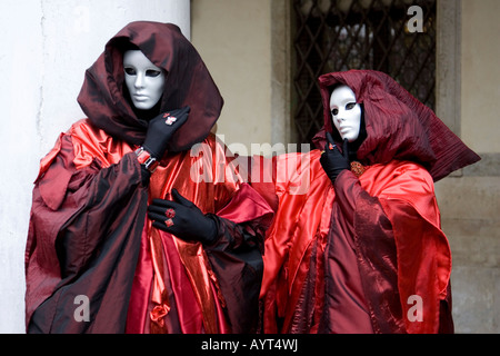Due persone che indossano rosso-nero costumi, incappucciati mantelli e maschere, il Carnevale di Venezia il Carnevale di Venezia, Italia Foto Stock