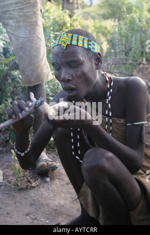 Africa Tanzania Lago Eyasi Hadzabe uomo fumo da un tradizionale tubo di argilla piccola tribù di cacciatori-raccoglitori Foto Stock