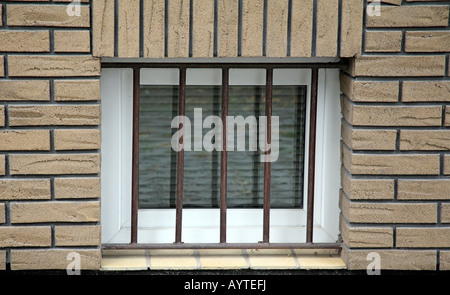 Una finestra del seminterrato, impostato in un edificio di mattoni, e arrugginite le barre di sicurezza. Foto Stock