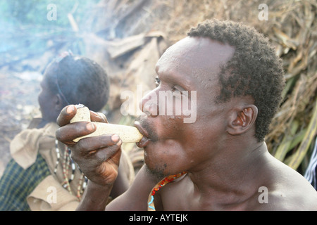 Africa Tanzania Lago Eyasi Hadzabe uomo fumo da un tradizionale tubo di argilla piccola tribù di cacciatori-raccoglitori Foto Stock