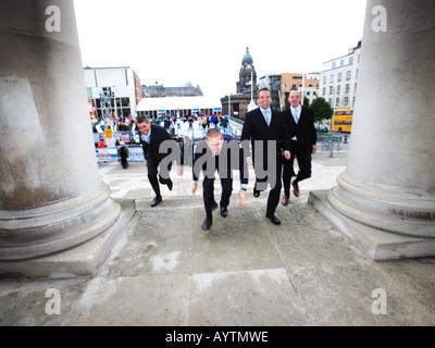 Quattro uomini d'affari 4 che pongono in esecuzione in Leeds Millennium Square per un servizio fotografico commerciale Foto Stock