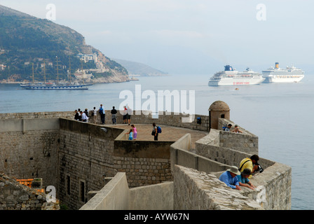 La sezione di parete della città, paese vecchio di Dubrovnik, Croazia, con due navi da crociera e alla replica della nave a vela in background Foto Stock