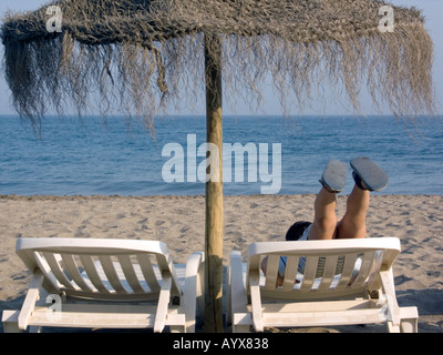 Ragazzo sul lettino a giocare con i suoi piedi in aria, Carvajal beach, Fuengirola, Costa del Sol, Spagna, Europa Foto Stock