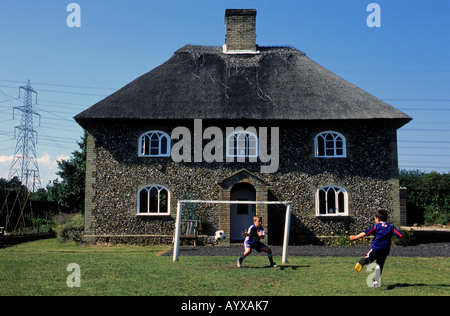 I bambini giocando una partita di calcio nel giardino della loro casa in Suffolk, Regno Unito. Foto Stock