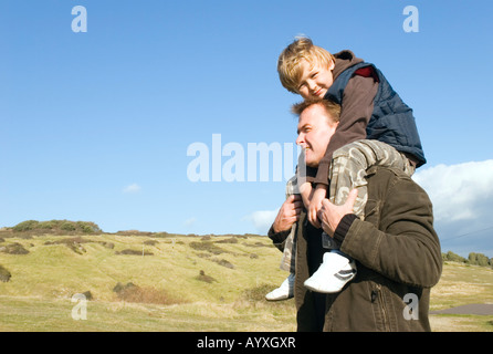 Padre porta il suo figlio di 8 anni sulle spalle durante una giornata fuori in campagna. Foto Stock