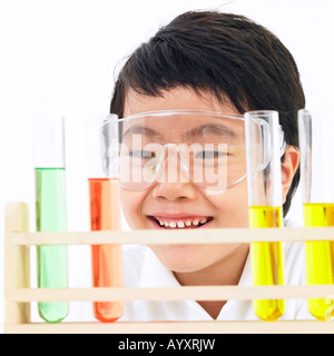 Un ragazzo studente facendo un esperimento scientifico con indossare gli occhiali di protezione Foto Stock