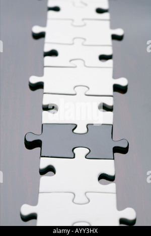 Un nero pezzo del puzzle tra bianco pezzi di puzzle Foto Stock