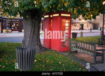 Due tradizionali cabine telefoniche rosse sotto un cavallo castagno al crepuscolo in Worcestershire village di Broadway Foto Stock