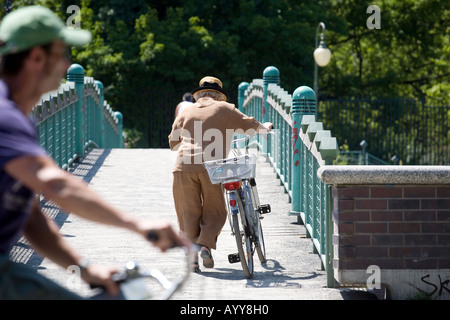 Un anziano ciclista spinge la sua bicicletta su un ponte pedonale a Berlino Germania Foto Stock