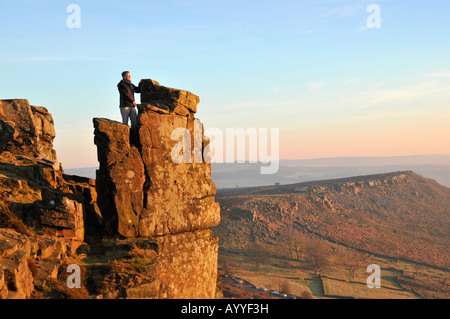 L'uomo a guardare il sole andare giù sul bordo Froggatt nel Parco Nazionale di Peak District Derbyshire Inghilterra Foto Stock