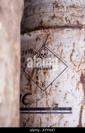 Vecchi barili metallici corrosivi con un cartello di avvertenza velenoso per cranio e ossa incrociate con il numero 6 su una superficie arrugginita e resistente agli agenti atmosferici. Foto Stock