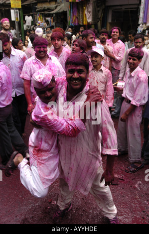 Gruppo di uomini indiani che ballano per la strada di nuova Delhi durante il festival Holi a Paharganj, festeggiando con la polvere rosa e la gioia. Foto Stock