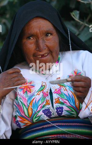 Isla Amantani--Lago Titicaca--Bolivia -- Un indigeno isola peruviana donna in abiti tradizionali sorrisi come lo tesse un cappello. Foto Stock