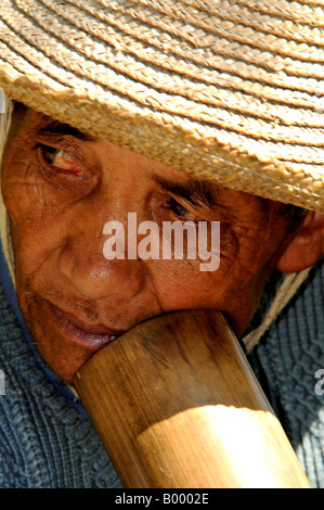 Un Hani Akha uomo fumi attraverso il grande tubo di bambù Foto Stock