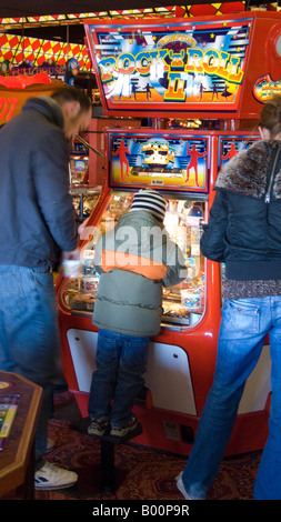 I genitori con bambini al penny macchina cade in un mare di divertimento arcade Foto Stock