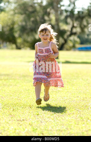 La felicità è in esecuzione nel parco in una giornata di sole, quattro anni di bambina in piena esecuzione, entrambi i piedi da terra. Foto Stock