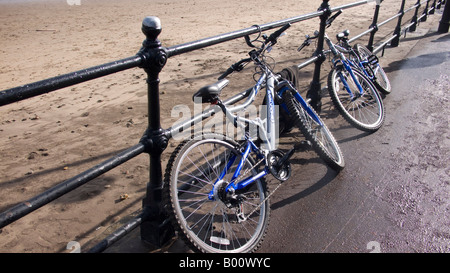 Due biciclette bloccato al lungomare ringhiere in metallo Foto Stock
