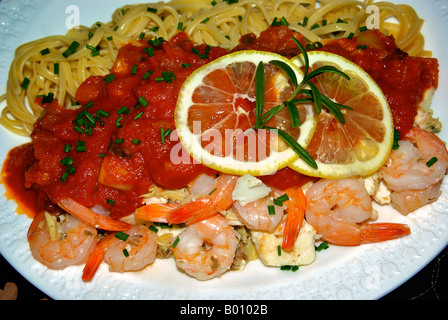 Pesce piatto linguine con gamberetti, halibut, e vongole, in una ricca salsa di pomodoro con limone, aglio, cipolla, erba cipollina e cipolla verde. Foto Stock