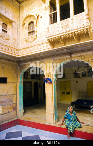 India Rajasthan, Jaiselmer, Patwon Ki Haveli. Tradizionalmente condita lady rilassato nel cortile principale. Foto Stock