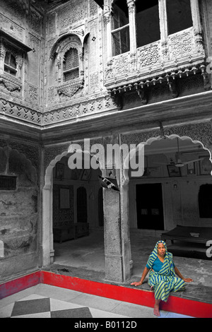 India Rajasthan, Jaiselmer, Patwon Ki Haveli. Tradizionalmente condita vestito lady rilassato nel cortile principale. Foto Stock