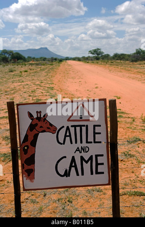 La Namibia, Regione di Erongo. Dove una pista sterrata interseca una bussola farm, un segno sulla strada mette in guardia contro il pericolo di accelerazione. Foto Stock