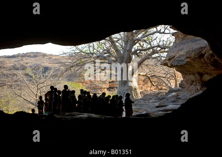 Mali, Paese Dogon. I bambini si riuniranno presso l'entrata di Bongo tunnel che è una formazione rocciosa naturale nei pressi di Sangha. Foto Stock