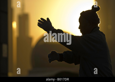 Albe su skyline come uomo anziano esercizi tai chi, il Bund, Shanghai, Cina Foto Stock