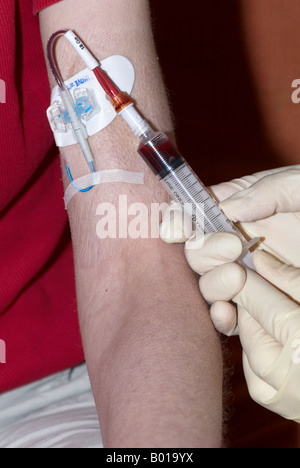 Prelievo di sangue da un picc line i cateteri inseriti centralmente perifericamente con una siringa e indossando i guanti chirurgici Foto Stock