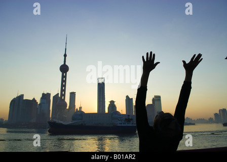 Albe su skyline come uomo anziano esercizi tai chi, il Bund, Shanghai, Cina Foto Stock