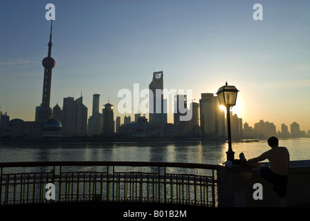 Albe su skyline come l'uomo esercita il tai chi, il Bund, Shanghai, Cina Foto Stock