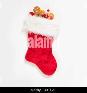 Calza di Natale ripieni con delizie assortite e dolci su sfondo bianco Foto Stock