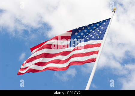 Una bandiera americana sbattimenti nel vento insieme contro un cielo blu con nuvole. Foto Stock
