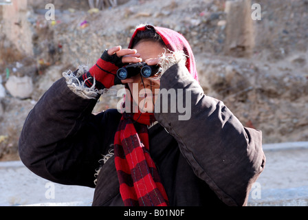 Un felice donna tibetana usare il binocolo Foto Stock