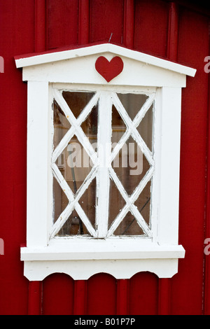 Finestra bianca su una parete rossa con un cuore rosso Foto Stock