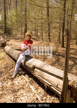 La donna caucasica (50-55) si appoggia sul registro durante le escursioni su un sentiero al fiume Davidson campeggio nei pressi di Brevard North Carolina USA Foto Stock
