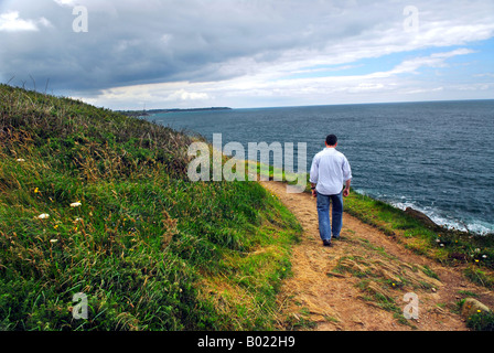 Un uomo che cammina su un sentiero escursionistico lungo le coste della Bretagna Francia Foto Stock